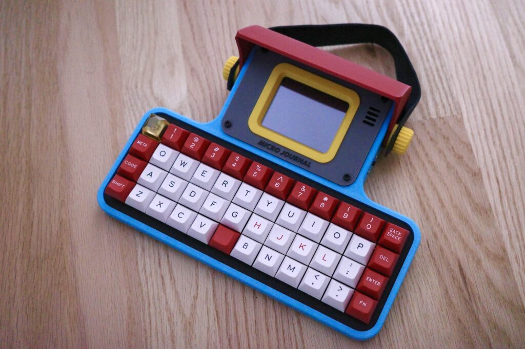 A small, colourful device dedicated to writing. It features a compact keyboard layout, and a small screen to view your writing.