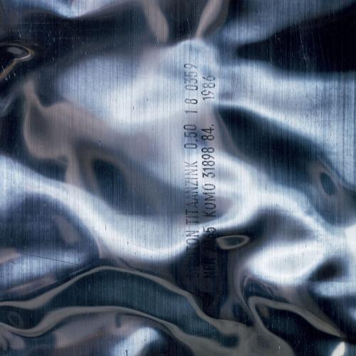 Album cover for New Order - Brotherhood. It shows a white, blue wavy, almost liquid looking pattern with some text stamped on to it.
