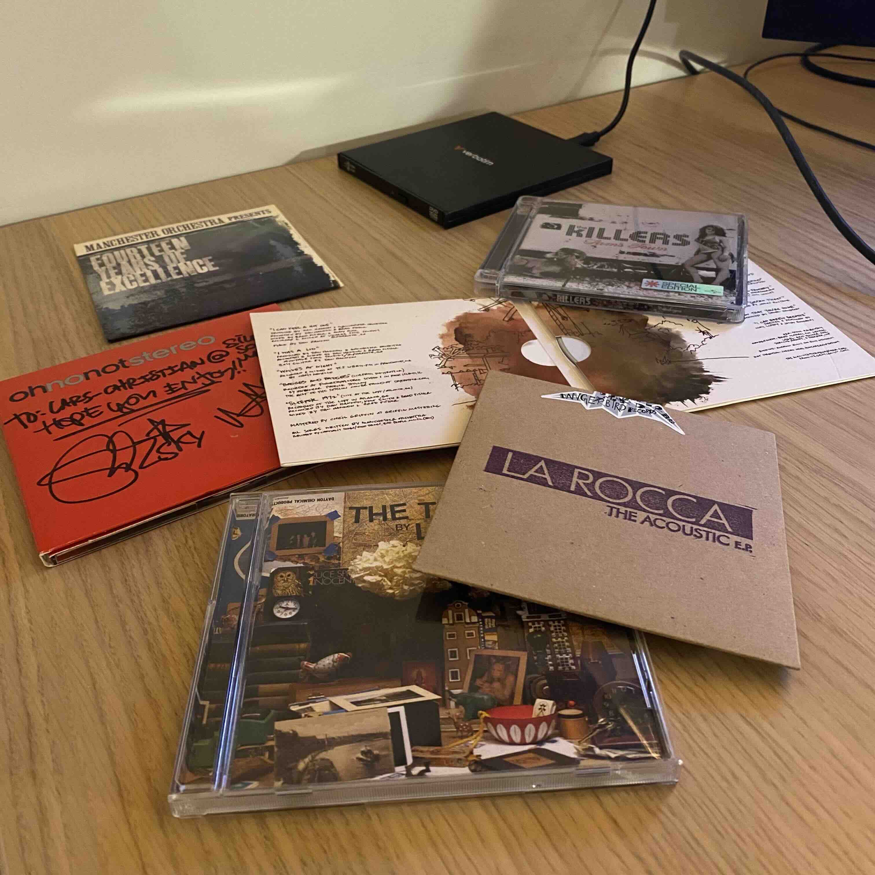 Photo of a few CDs and an external CD drive all placed on a desktop