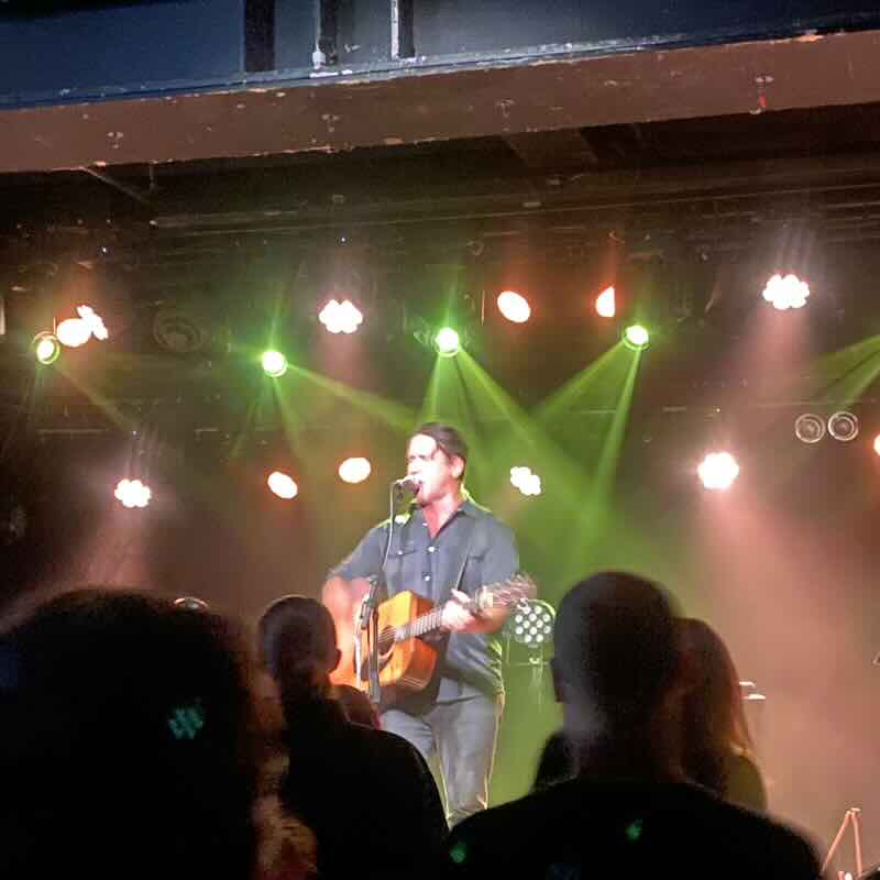 Chuck Ragan performing alone with a guitar on a stage